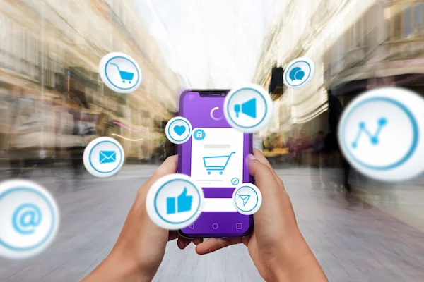 celular en mano con iconos que refieren a compras, interacciones, compartidos, anuncios y más