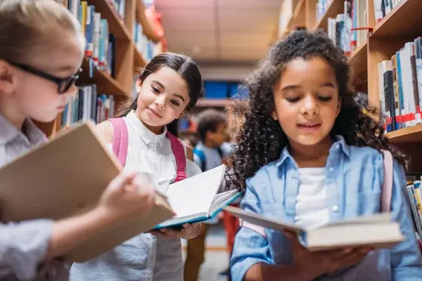 niños leyendo libros en una biblioteca haciendo valer su derecho a la educación en el día internacional de la educación