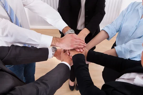 empleados comprometidos con la responsabilidad social empresarial poniendo sus manos unas sobre otras, demostrando compromiso