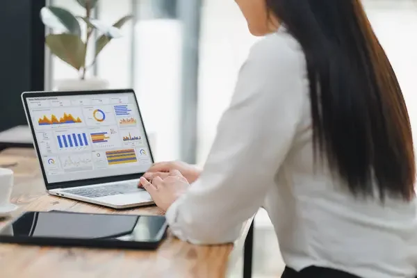 mujer empresaria de espaldas revisando los indicadores de productividad en su computadora