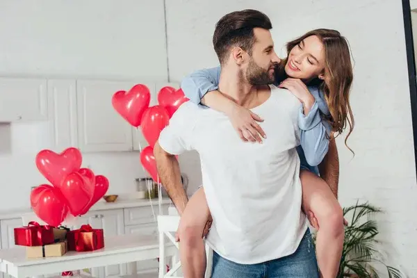 pareja abrazándose en el día de san valentín, con globos de corazón en el fondo