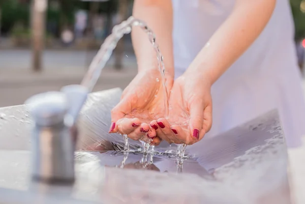 grifo de agua abierto mojando las manos de una persona en primer plano