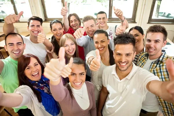 gente sonriendo y mostrando el dedo pulgar levantando a modo de celebración del día internacional de la felicidad