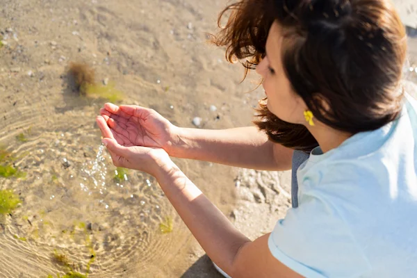 mujer recogiendo agua con sus manos