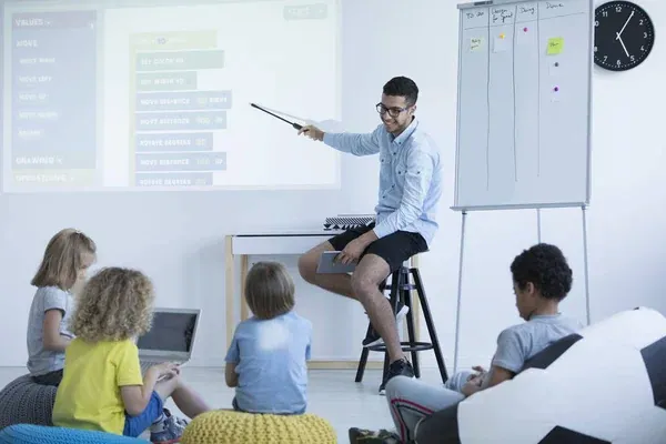 maestro joven dando clases a sus alumnos, apoyándose del proyector para usarlo como pizarra