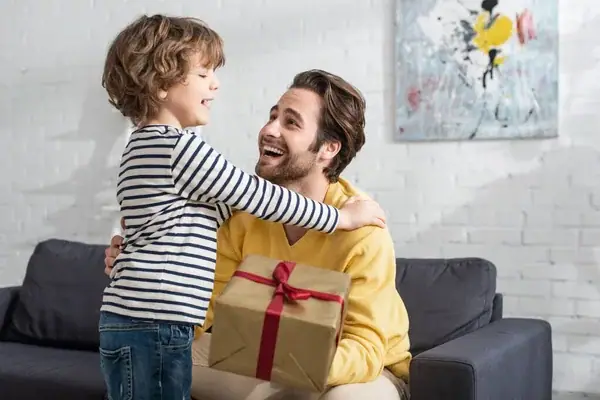 padre sonriendo recibiendo regalo de su hijo en el día del padre
